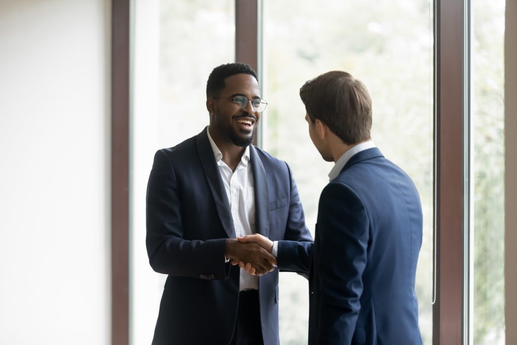 Overjoyed multiracial business partners shake hands after meeting